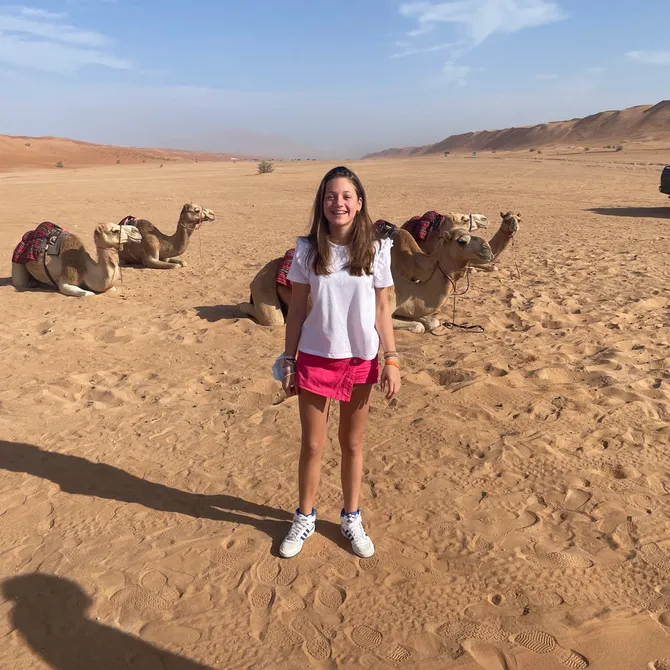 Meisje bij kamelen in woestijn van Oman