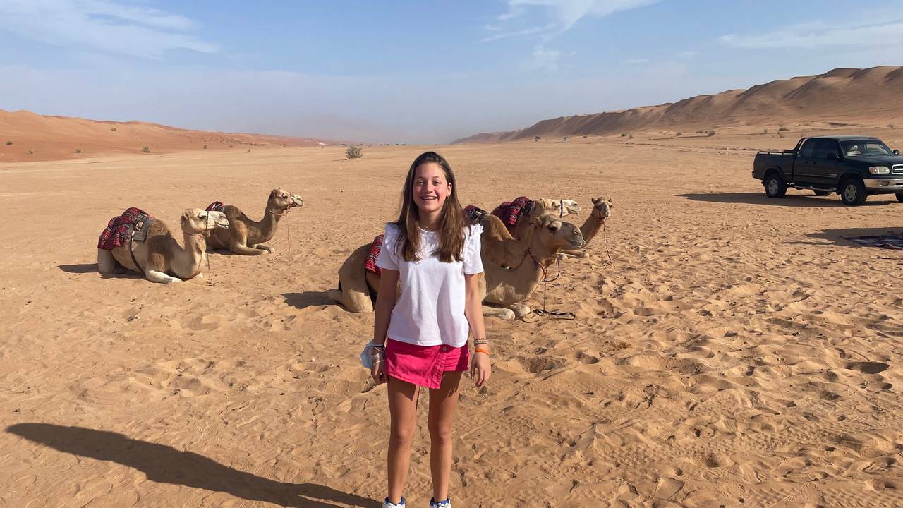 Meisje bij kamelen in woestijn van Oman